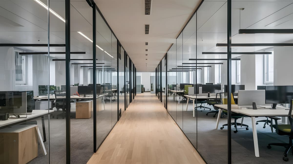 Open space d'une entreprise avec plusieurs bureaux et ordinateurs.